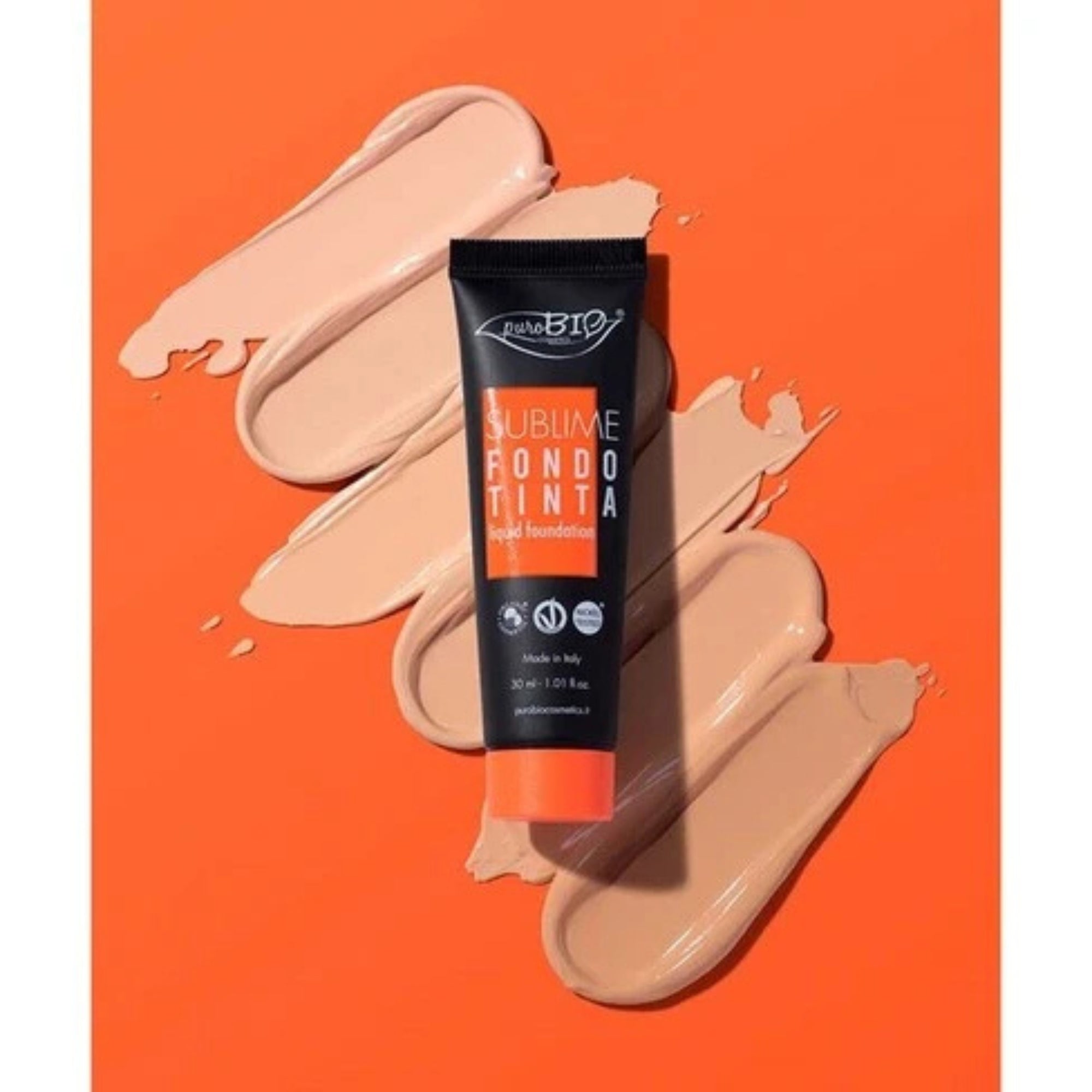 Tube of foundation with beige swatches on an orange background