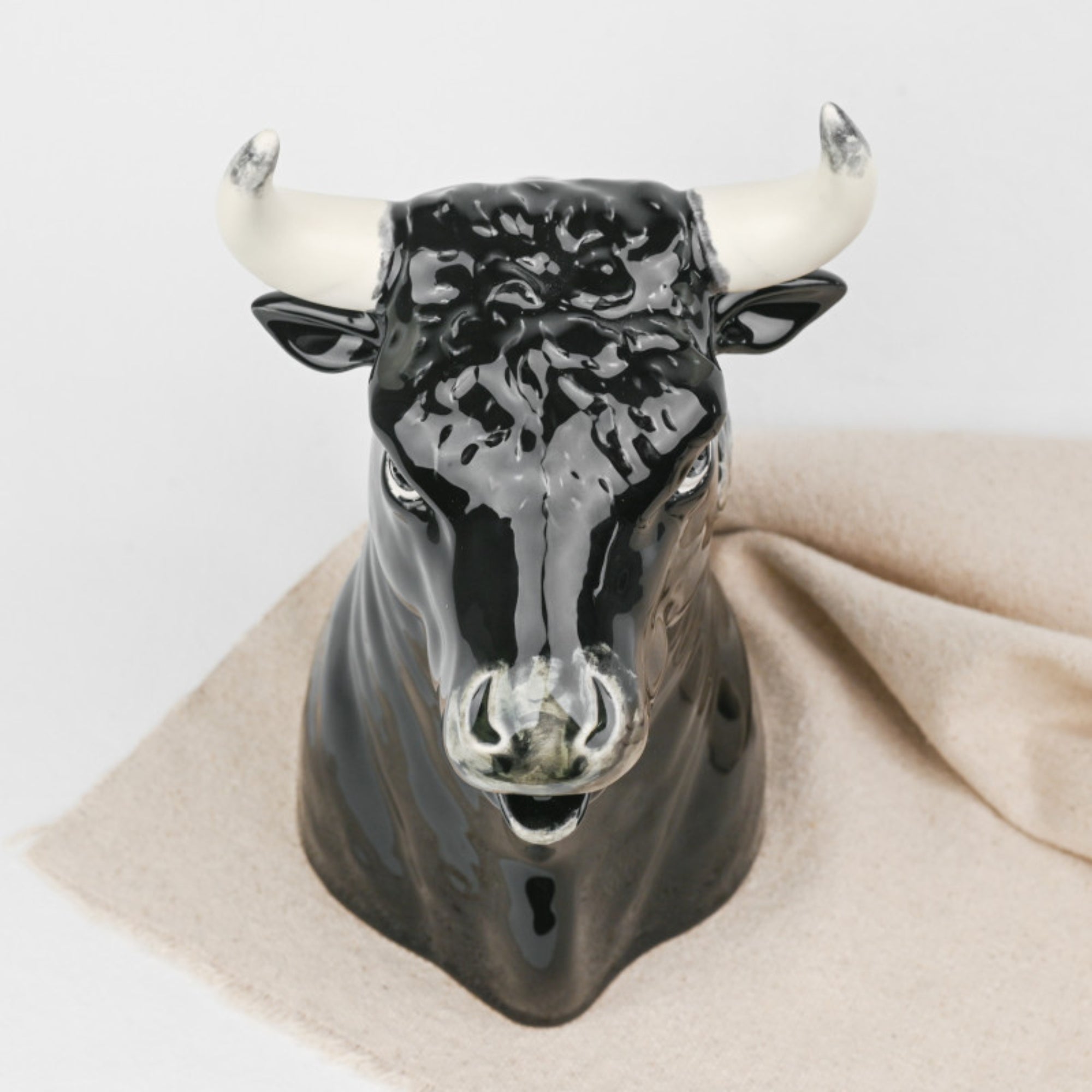 Bordallo Pitcher Bull on a beige cloth with a white background