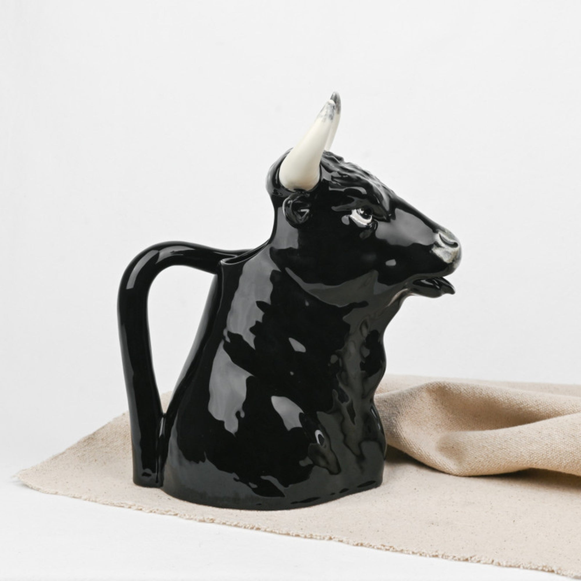 Bordallo Pitcher Bull on a beige cloth with a white background sideways view