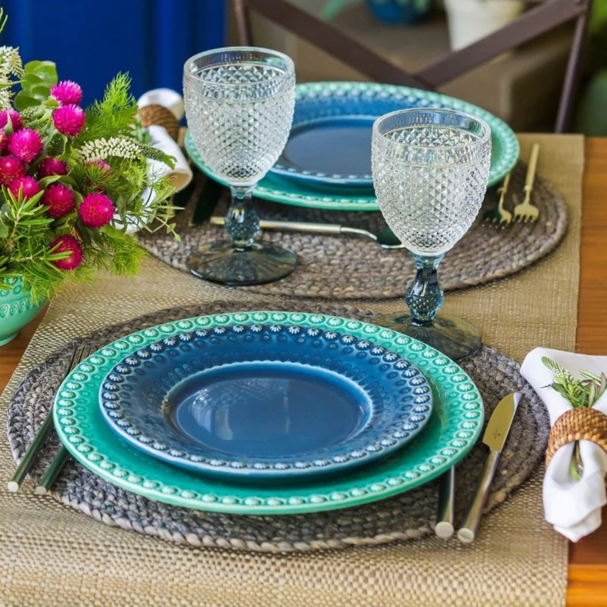Bordallo Pinheiro Fantasy Dinner Plate, glasses, and cutlery on a woven placemat.