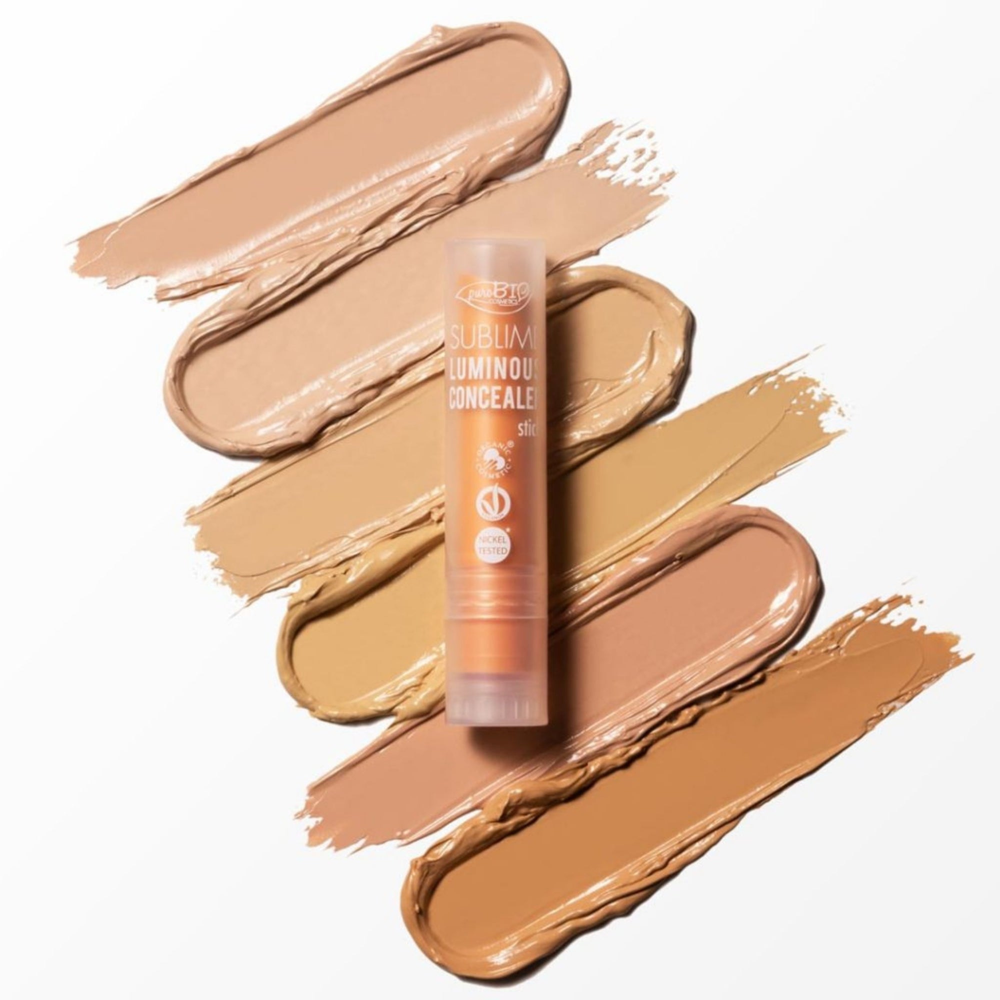 PuroBIO Luminous Concealer Stick with swatches of beige makeup on a white background