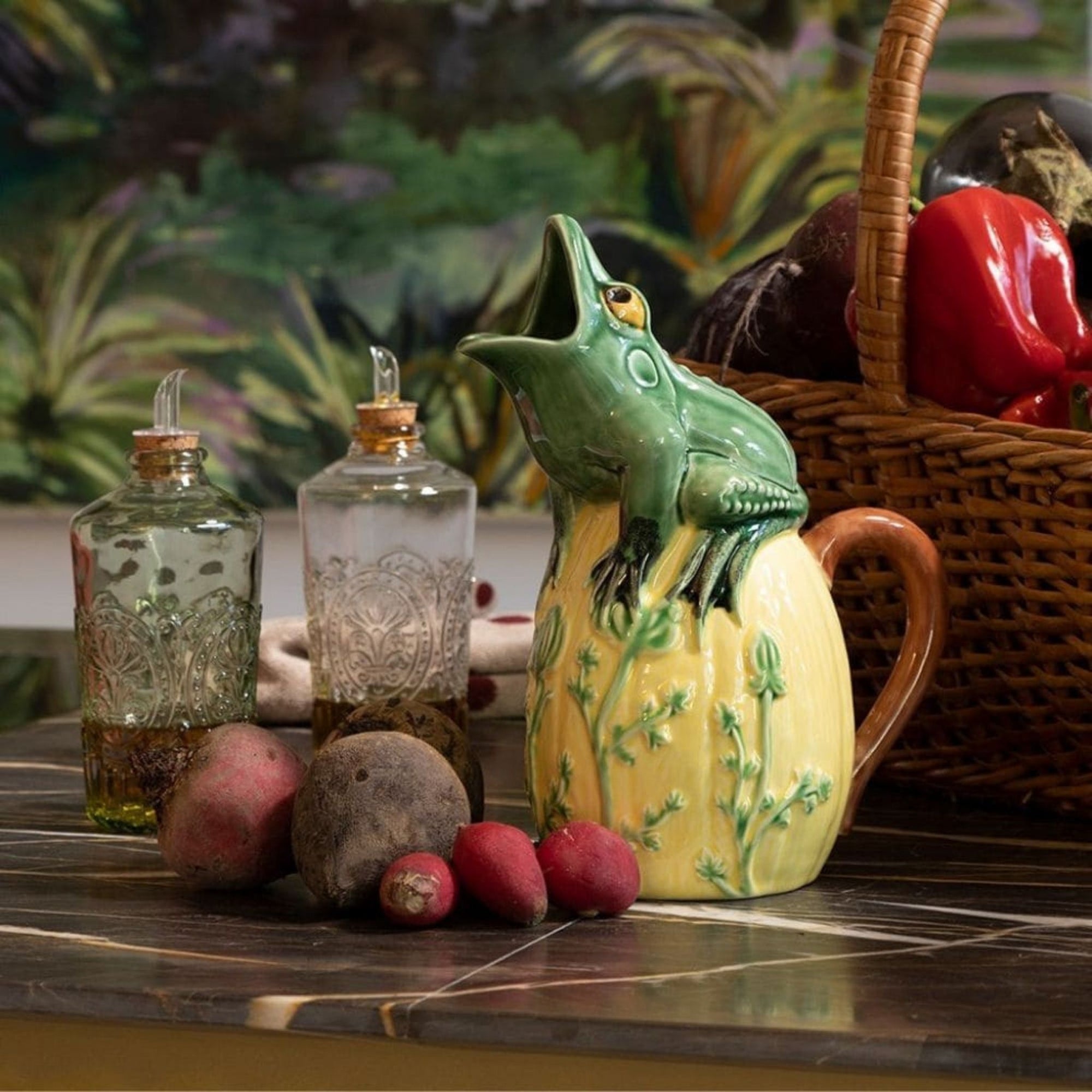 Bordallo Pinheiro Frog Pitcher on a table with decorative bottles and vegetables