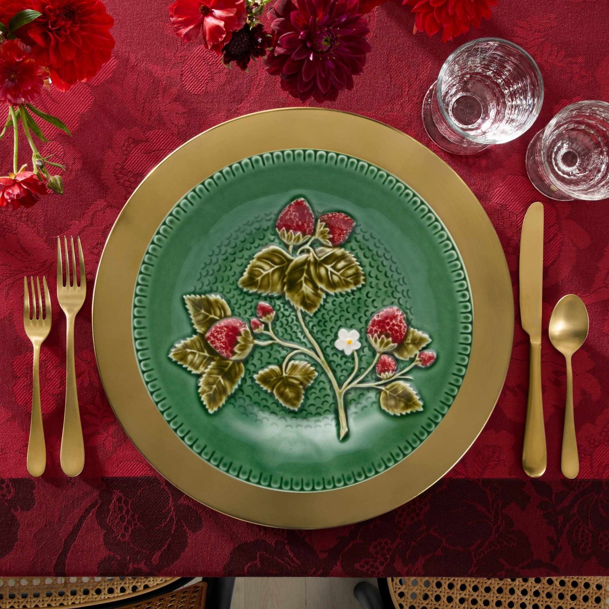Bordallo Strawberries Fruit Plate on a red tablecloth with gold cutlery.